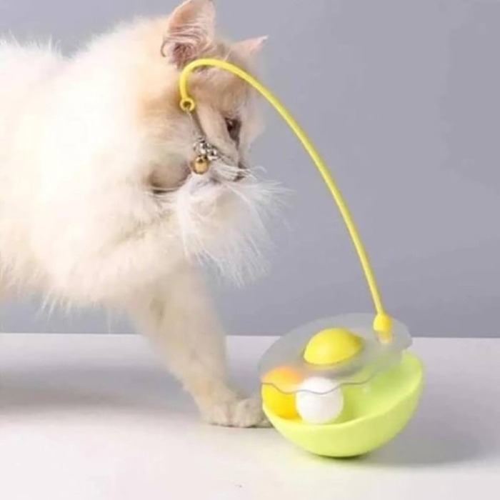 Zilli Catnip Toplu Hacıyatmaz Kedi Oyuncağı-2025 Zilli ve catnipli hacıyatmaz kedi oyuncağı, sarı renkli tabanı üzerinde şeffaf top haznesi olan, ucunda tüylü olta bulunan sallanan oyuncakla oynayan beyaz kedi